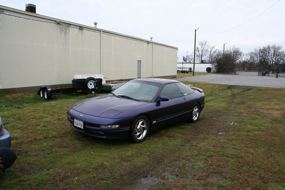 Purple 1996 Ford Probe coupe parked on grass next to a trailer