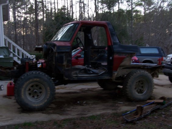 red and black pickup truck project, missing doors and hood, large tires