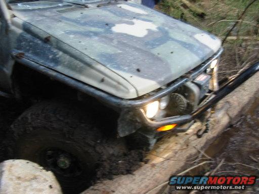 Camouflaged off-road vehicle front stuck in mud with winch