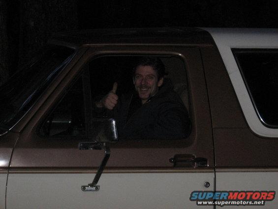 Man in driver's seat of 1987 Ford Bronco, giving thumbs up. Two-tone brown and white paint