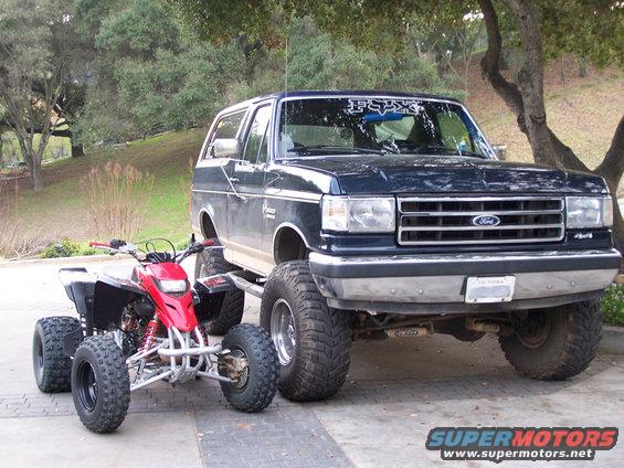 Lifted 1991 Ford Bronco parked next to a red ATV