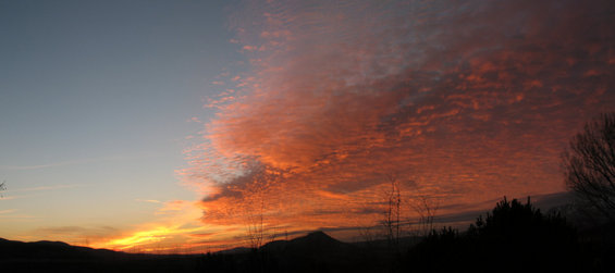 Sunset sky with vibrant orange and red clouds over silhouetted hills