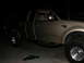 1999 Ford F-150 - A gold pickup truck is parked on a paved surface at night, with broken glass on the ground in front of it.