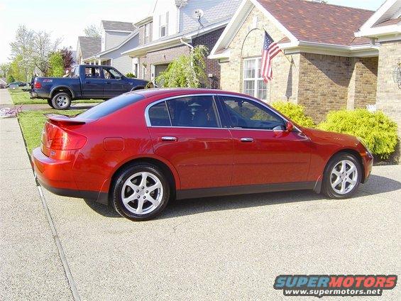 Red sedan parked in driveway, blue pickup truck in background