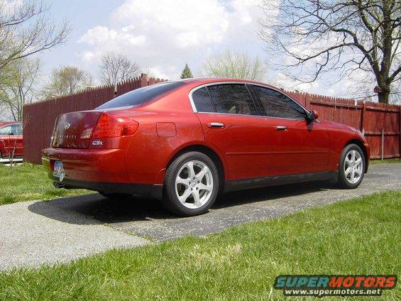 2004 Infiniti G35 sedan, rear 3/4 view, parked on a paved driveway with grass and a wooden fence
