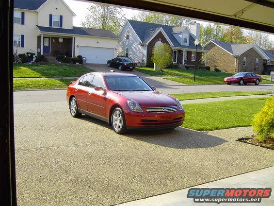 Red 2004 Infiniti G35 sedan parked in driveway, another car in background