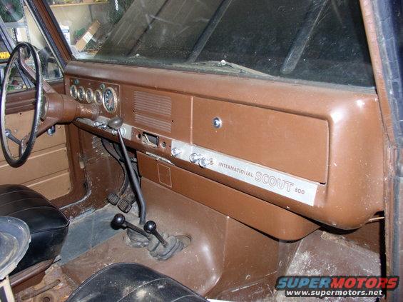 Brown dashboard of a 1967 International Scout 800 with a metal trim plate reading "INTERNATIONAL SCOUT 800"