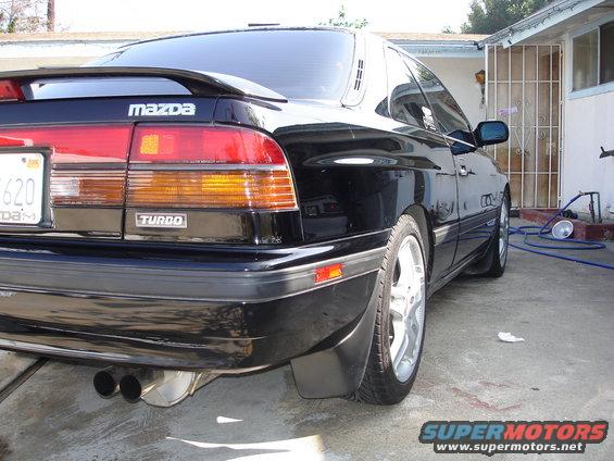 Black Mazda with a rear spoiler and dual exhaust pipes. The 'Turbo' badge is visible