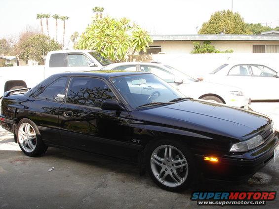 Black 1989 Mazda MX-6 GT parked outside with other cars behind it