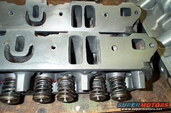 Engine cylinder heads with valve springs visible, Supermotors.net logo