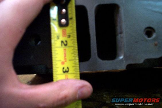Cylinder head part being measured with a tape measure showing approximately 2.5 inches
