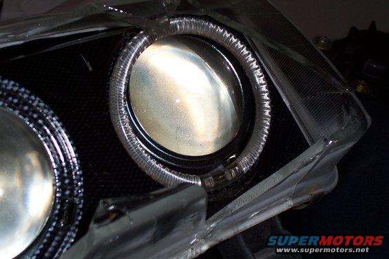 Close-up of a car headlight projector with a halo ring