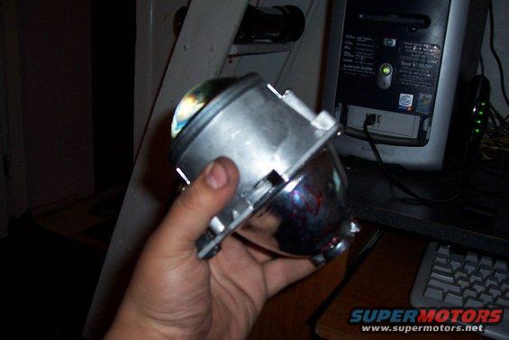 Hand holding a projector headlight assembly with a chrome reflector