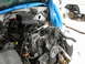 1991 Ford Bronco - Engine bay components are visible, with a blue tarp covering some of the engine. Another vehicle is partially visible in the background.