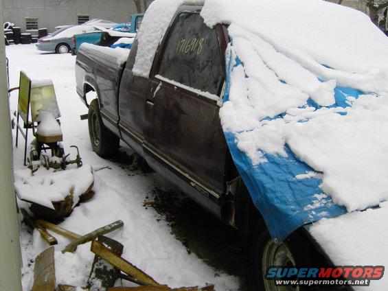 Maroon truck covered in snow, partially with a blue tarp. Visible number 1716918 on window