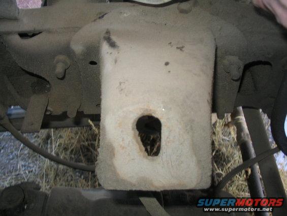 Close-up of a dusty truck frame component with a hole