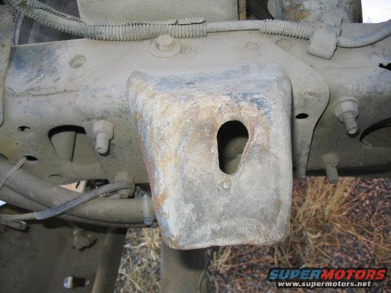 Close-up of a rusty metal bracket on a truck frame, with bolts and wiring visible