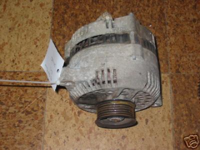Gray metal alternator with a pulley and a white tag attached