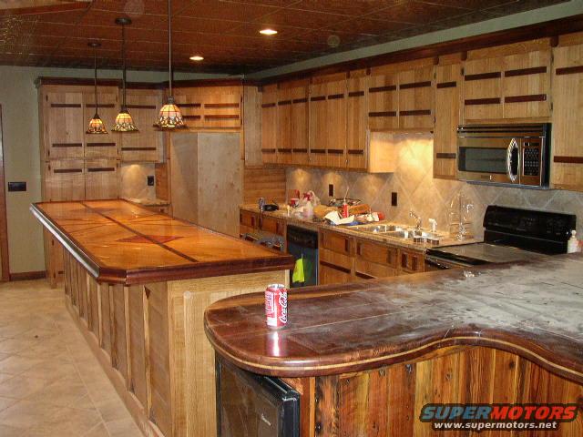 Kitchen with wood cabinets, granite countertops, and a large wooden bar. A Coca-Cola can sits on the bar
