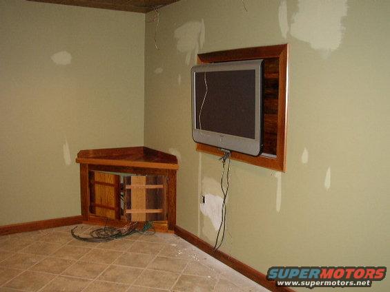 Interior scene with mounted television and wooden corner cabinet