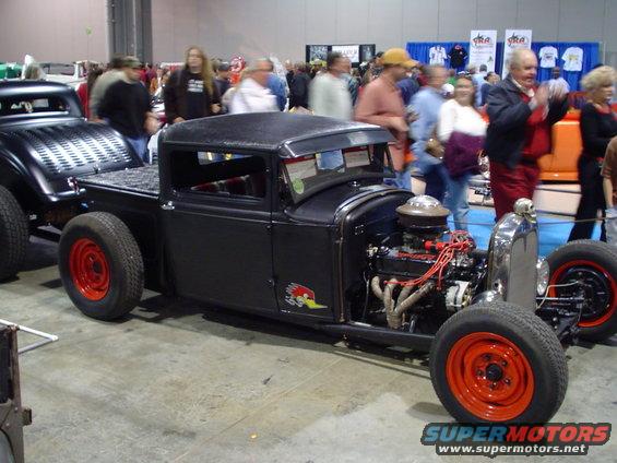 Black hot rod pickup truck with exposed engine and red wheels