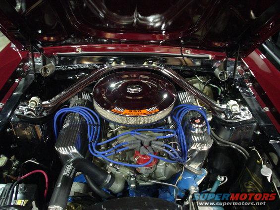 Close-up of a Ford 390 High Performance V8 engine with blue spark plug wires and chrome accents