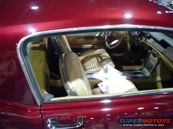 Red car interior with tan seats and dashboard, viewed through the passenger window
