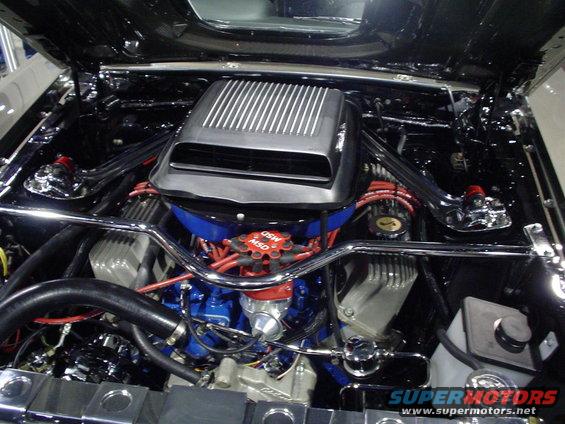 engine bay with chrome strut braces, blue engine block, and red spark plug wires