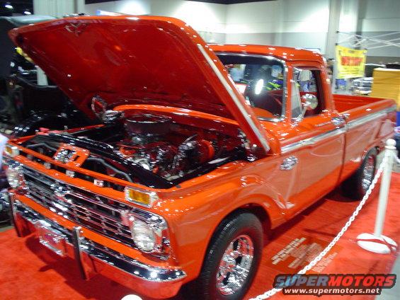Orange 1965 Ford F-100 pickup truck with hood open, showing engine
