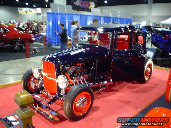 Dark blue hot rod with red interior and orange wheels, seen from a 3/4 front angle