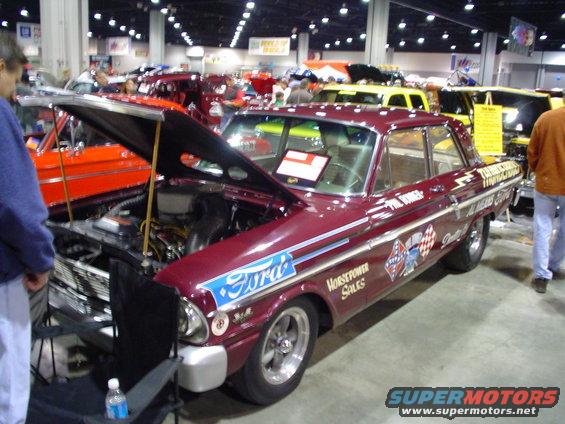 Maroon 1960s Ford sedan with 'Ford' and 'Horsepower Sales' decals, hood open