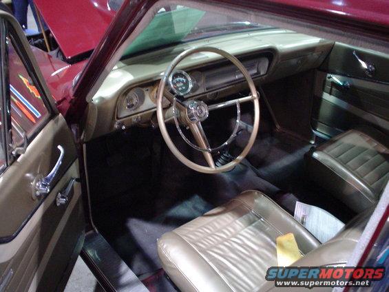 Car interior with tan seats, steering wheel, and dashboard. A "SUPERMOTORS" watermark is visible