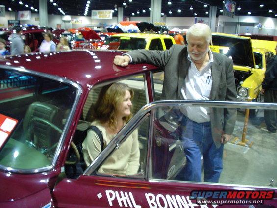 Maroon car interior with woman, man leaning on door, text "PHIL BONNE" on side