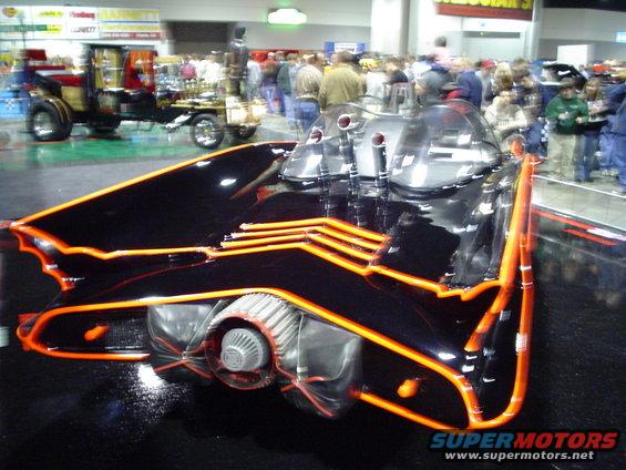 Black custom car with orange trim and exposed engine detail, viewed from the rear