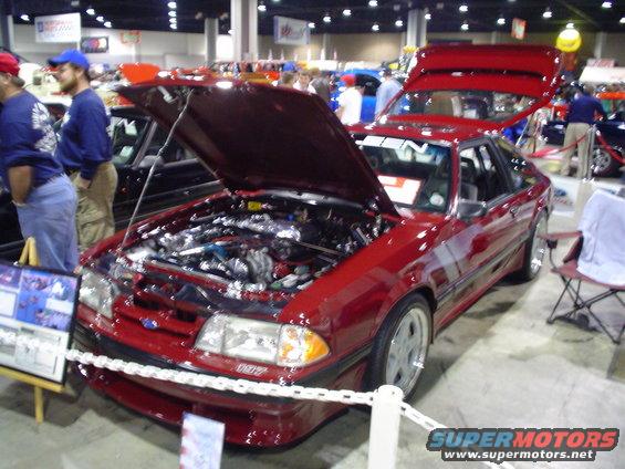 Red coupe with hood and trunk open, showing the engine. It has a 5.0 badge on the front