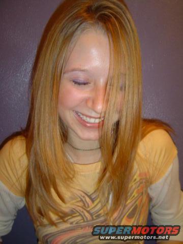Young woman with blonde hair smiling, wearing a yellow shirt with a graphic print. Text at bottom reads SUPERMOTORS