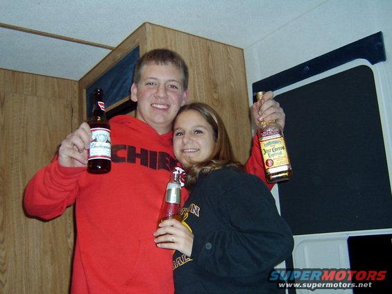 Guy in red hoodie and girl in black shirt holding beer and tequila bottles
