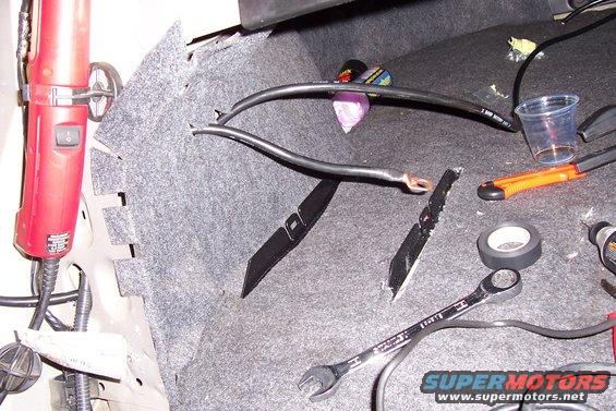 Battery cables and tools in trunk, including a red grinder and wrench
