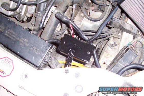 Engine bay with fuse box, wiring harness, and black relay box. STOP sign sticker visible