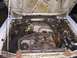 1988 Ford Mustang - The engine bay of a 1988 Ford Mustang shows its V8 engine, alternator, and battery, with signs of rust.