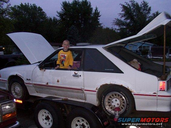 1988 Ford Mustang on trailer, hood and trunk open, child in driver's seat