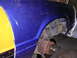 1988 Ford Mustang - A blue and yellow 1988 Ford Mustang shows rust around the wheel well and suspension.