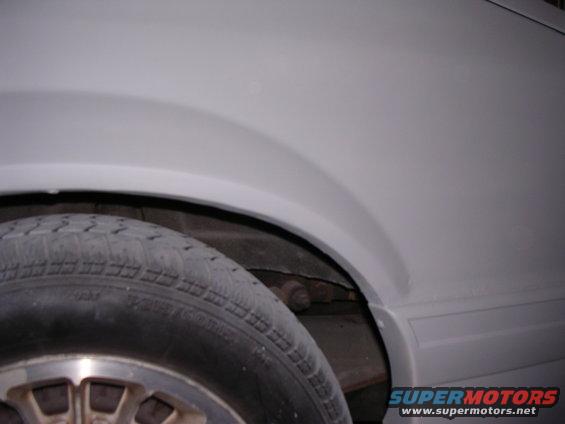 Close-up of a car's rear fender and tire, painted gray