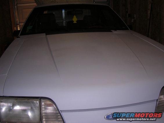 White car hood and headlight with a Supermotors logo visible