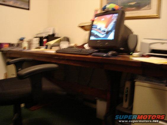 Office desk with computer monitor displaying a car on screen