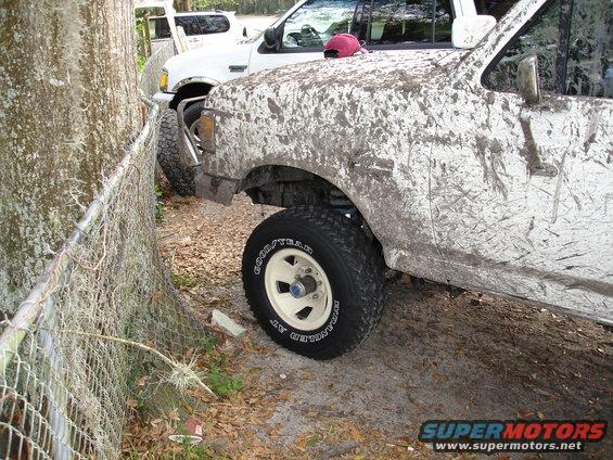 Mud-covered 1992 Ford F-150 front fender and wheel, parked next to a white Ford SUV