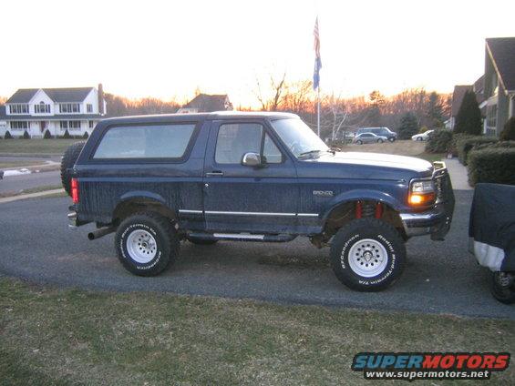 Blue 1994 Ford Bronco with aftermarket wheels and tires parked in a driveway
