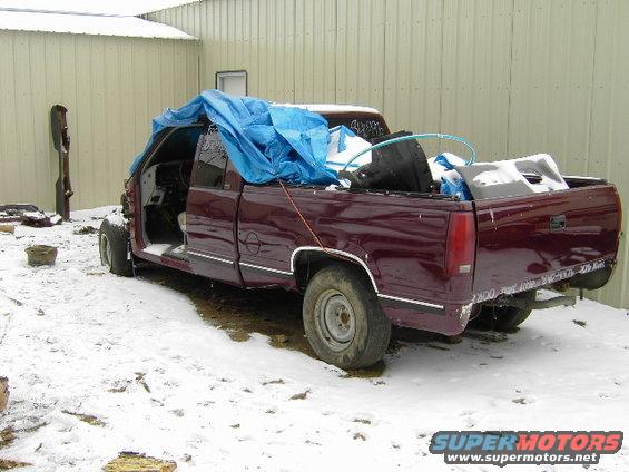 1997 Chevrolet C/K Pickup with blue tarp covering the cab and bed, parked in snow