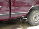 1997 Chevrolet C/K Pickup - The side of a maroon 1997 Chevrolet C/K Pickup truck is visible, including the fuel door and rear wheel.