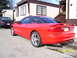 1994 Ford Probe - A red 1994 Ford Probe is parked next to a trailer home, with a dark sedan visible behind it.